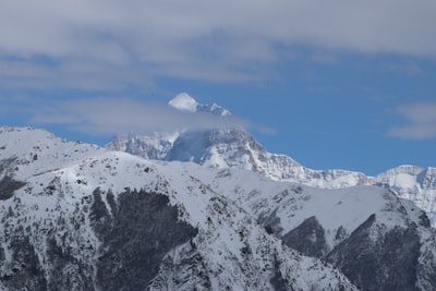 峰会的山雪覆盖着白色和蓝色的天空下
